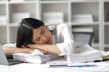 Business woman at a desk in the office who is tired from overwork.