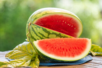 Watermelon  on wooden table, Fresh Giant Seedless Watermelon with slices on blurred greenery background.