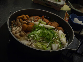 Cooking traditional Japanese nabemono seafood soup with shrimps, mushrooms and vegetables