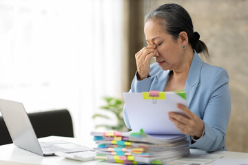 Senior businesswoman is stressed from doing too much paperwork.