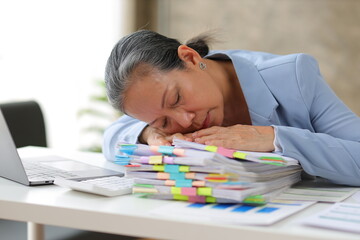 Senior businesswoman is stressed from doing too much paperwork.