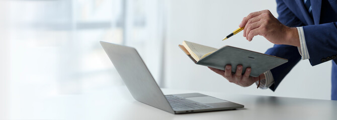 Businessman working on laptop, checking email, sending information online on desk Hold a notebook...