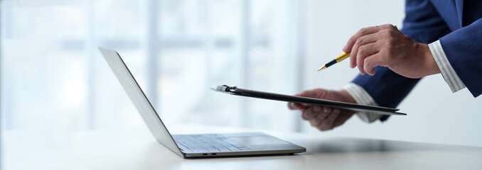 Businessman working on laptop, checking email, sending information online on desk Hold a work file...