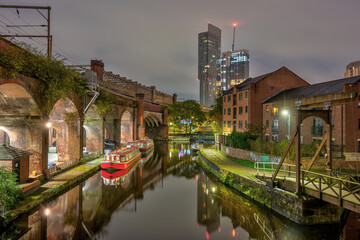 Castlefield in Manchester, UK, at night, with a modern skyscraper in the back - 683185483