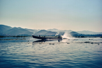 Vue d'un bateau &agrave; moteur passant sur le lac Inle au Myanmar avec les montagnes en toile de fond