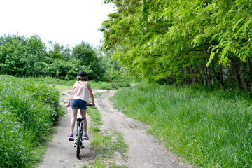 Naklejka premium Young girl cyclist enjoy the beautiful sunrise on summer forest trail