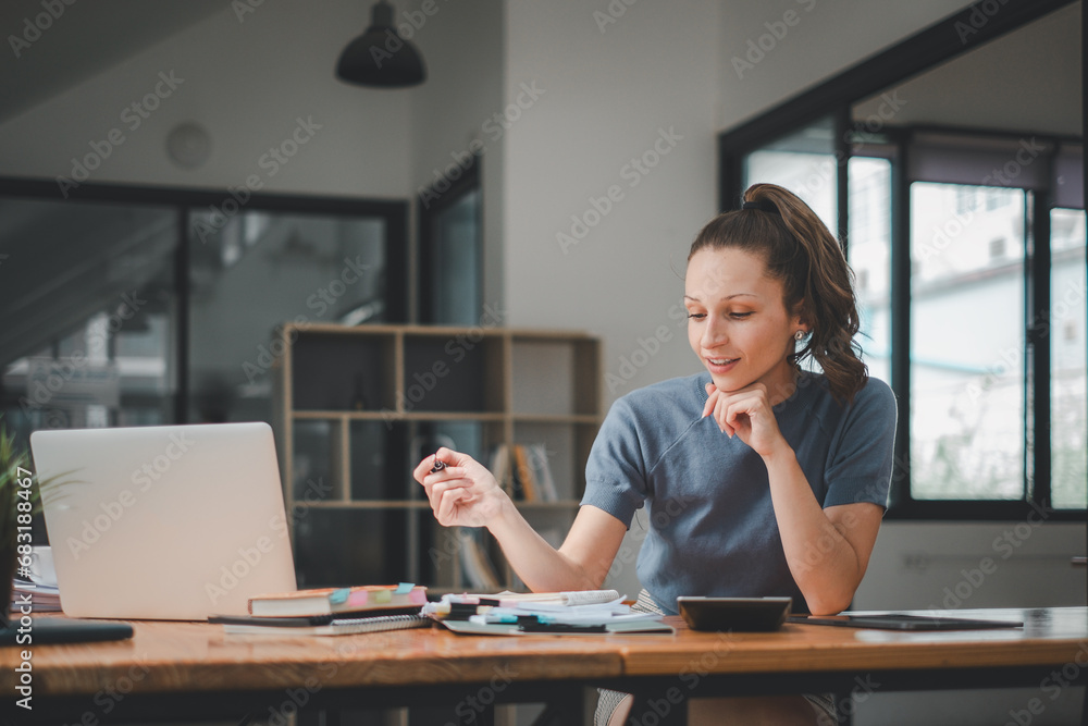 Poster smiling young woman using calculator and laptop computer to calculate financial report, working at o