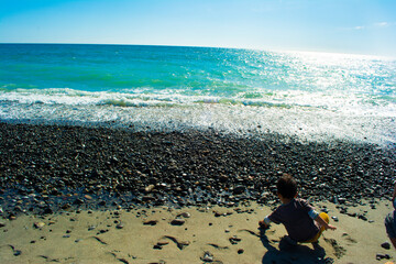 中田島砂丘の砂利で遊ぶ子どもの後ろ姿と青空