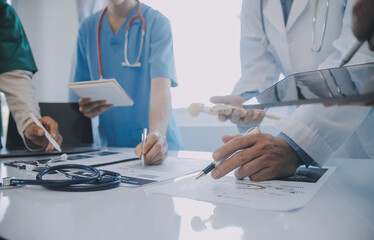 Multiracial medical team having a meeting with doctors in white lab coats and surgical scrubs...