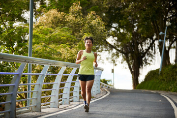 young asian woman running jogging exercising outdoors in park