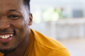 Happy african american man sitting on stairs at home, face close up, copy space
