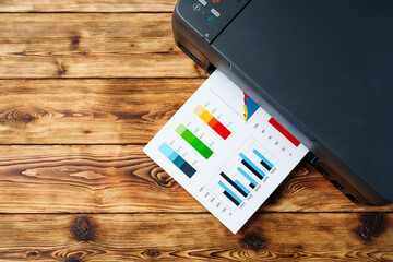 Modern laser printer with paper on wooden background