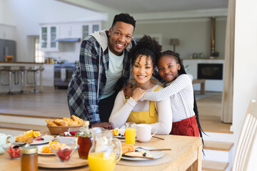Portrait of happy african american family embracing at table in dining room at home, copy space
