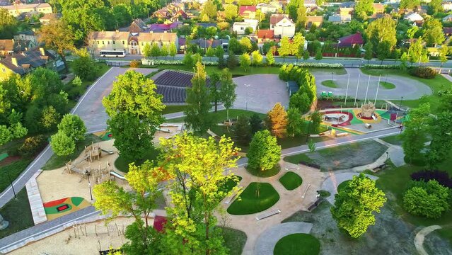 Children's Playground Area Surrounded by Trees in Warm Sunlight, Aerial Orbital Drone Shot.
