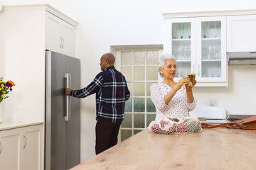 Diverse senior couple unpacking groceries in kitchen