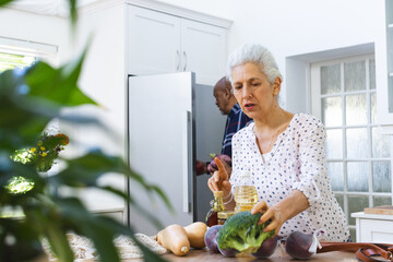 Diverse senior couple unpacking groceries in kitchen