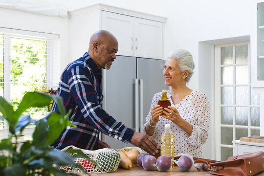 Diverse senior couple unpacking groceries in kitchen