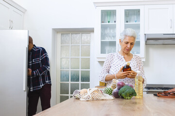 Diverse senior couple unpacking groceries in kitchen