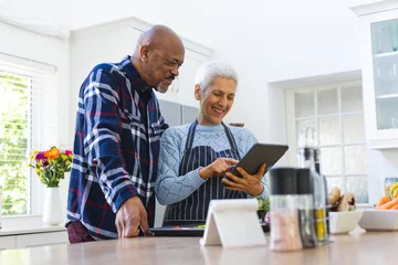  Happy diverse senior couple preparing meal using tablet in kitchen © WavebreakMediaMicro