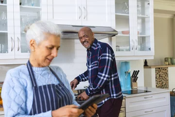 Poster Diverse senior couple preparing meal using tablet in kitchen © WavebreakMediaMicro