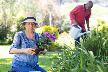 Diverse senior couple gardening in sunny garden