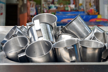 A pile of aluminum mugs in a sink in a fast food restaurant, Thailand