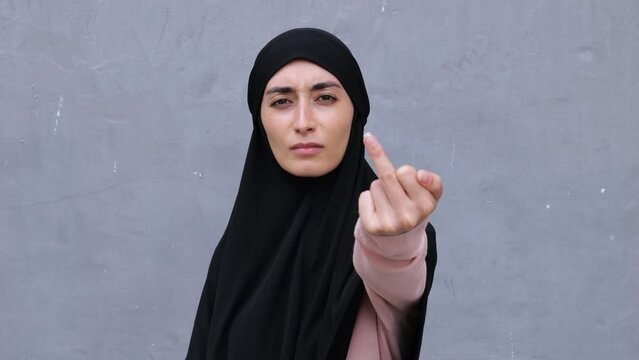 Disobedient Muslim woman in hijab shows offensive gesture. Hand gesture meaning in Western cultures Fuck you or go to hell. One gesture can say more than many expressive words of protest