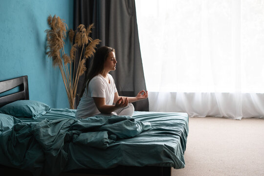 Morning meditation. Young relaxed woman practicing yoga zen on bed after waking up