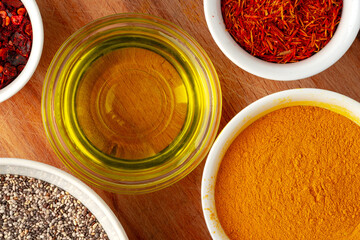 Bowls with oil and spices on wooden board top view