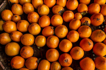 Ripe orange persimmons. on the table in the market. A bunch of organic persimmon fruits at a local farmers market in Dalat city, Vietnam. Persimmon background. Flat lay.