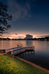 Obraz premium Sunset view on Xuan Huong lake, far away is Da Lat City with development buildings, transportation, market. Tourist city with center square of Da Lat city.