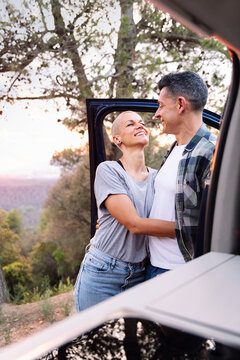 woman and man embracing next to their camper van admiring the landscape in the countryside, concept of couple adventure travel and active tourism in nature