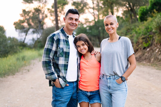 portrait looking at camera of a father, mother and daughter smiling happy in the countryside, concept of active tourism in nature and family outdoors activities