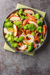 Broccoli, pecans, cranberries, carrots and apples come together to make an amazing salad with delicious flavors and textures closeup on the plate on the table. Vertical top view from above