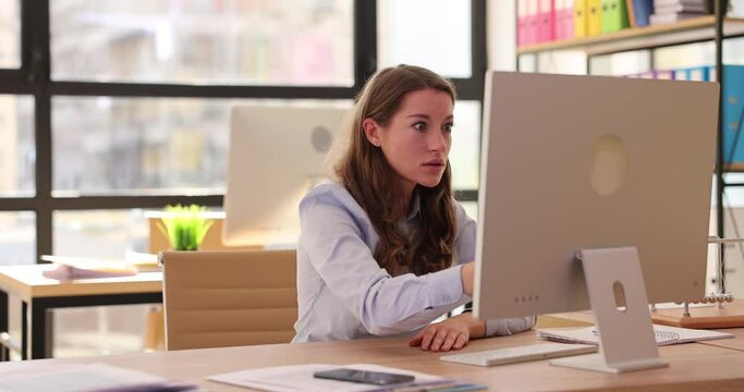 Young beautiful woman looking at laptop computer in office, disappointed and shocked and reading bad news on Internet