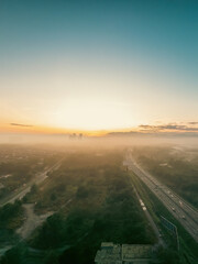 Aerial view of the golden sunrise near the highway in Malaysia with misty morning fog.