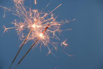 Two firework sparklers burning on blue background
