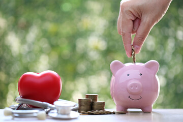 Piggy bank with stethoscope and red heart on green background,Save money for Medical insurance and Health care concept - obrazy, fototapety, plakaty