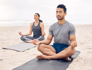  Couple of friends, lotus pose and beach meditation for zen fitness, calm exercise and mindfulness or holistic wellness. Young people in meditation, yoga by sea and ocean or nature for mental health © Azeemud/peopleimages.com