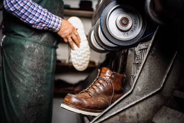 Handwerker, Schuster arbeitet hält einen Schuh und schleift die Sohle an Schleifmaschine. Im...