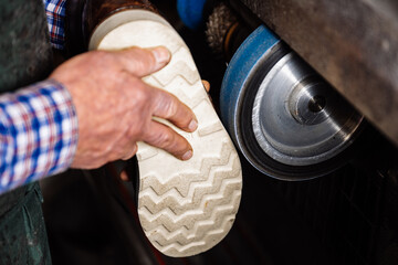 Handwerker, Schuster arbeitet hält einen Schuh und schleift die Sohle an Schleifmaschine. Im...