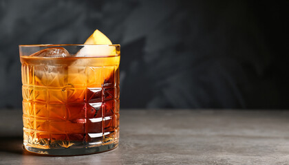 Glass of tasty Old Fashioned cocktail on table against dark background with space for text - obrazy, fototapety, plakaty