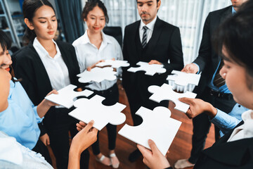 Multiethnic business people holding jigsaw pieces and merge them together as effective solution...