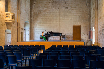 Kyrenia (Girne in Turkish), North Cyprus - October 24, 2023: There is a piano musician in the concert hall and the audience has not arrived yet in Bellapais Abbey.