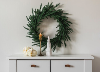Christmas decor of the living room - a Christmas tree wreath on the wall, a brass candlestick with...
