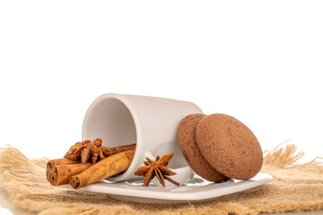Chocolate, cinnamon, star anise cookies with ceramic cup and saucer on jute napkin, macro, isolated...