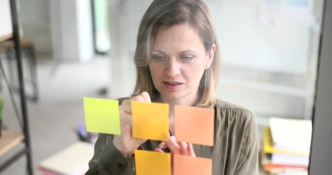 Business woman creates list of priority tasks standing behind glass wall. SEO or manager writes fresh ideas and interesting creative thoughts