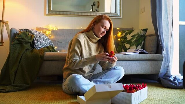 Red-haired young caring woman packing Christmas gifts for family winter day at home. Cosy tranquil atmosphere of warmth and care. Anticipation preparation New Year holidays vacation.