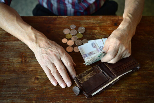The hands of an old man counting money. The concept of poverty, low income, austerity in old age.	