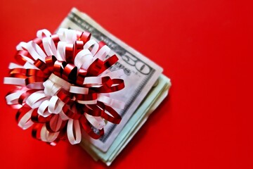 Red white ribbon ball with cash dollars money on blurred red background  - concept of bonus , money...